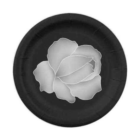 a black and white paper plate with a flower on the center, in front of a white background