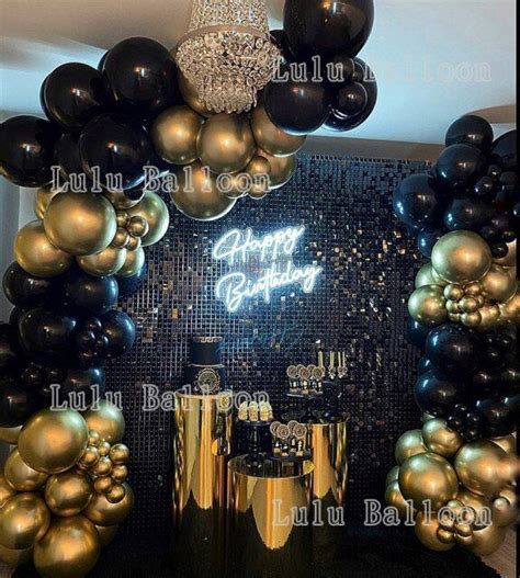 a birthday party with balloons and black and gold decorations on the ...