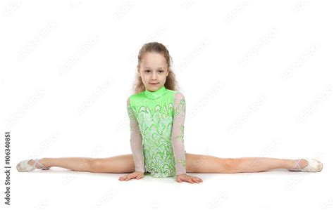 Gymnast cute little girl sitting on the floor. The child in the gymnastics suit doing the splits ...