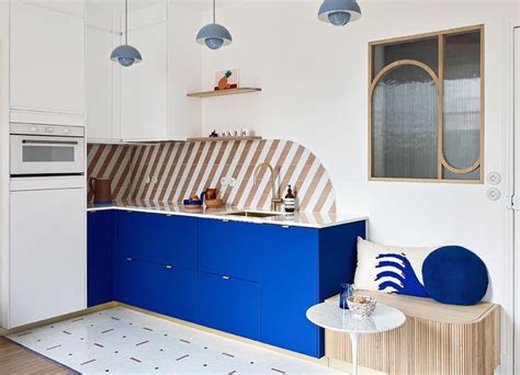 a kitchen with blue and white cabinets, an oven, sink and counter top in it