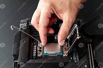 Computer CPU Installation. Hand of Master Installs Processor Chip on Computer Motherboard ...