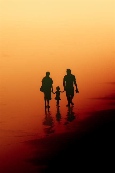 A family walking on the beach at sunset · Free Stock Photo