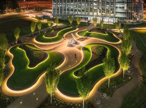 an aerial view of a park at night with illuminated paths and trees in the foreground