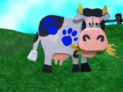 a cow that is standing in the grass with its paw print on it's face