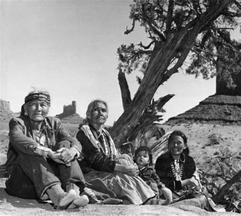 Navajo family sitting on ground by tree. Monument Valley, 1960’s.