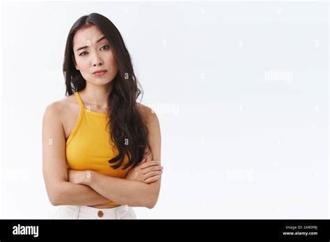 Skeptical, unimpressed pretty east-asian female in yellow top, cross ...