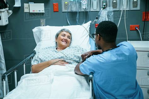 Nurse talking to patient in hospital bed - Stock Photo - Dissolve