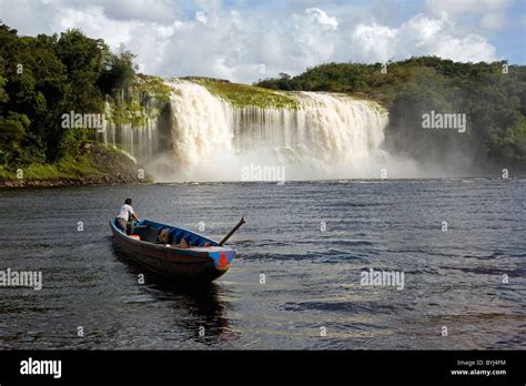 A Pemon tribe man while sailing with his boat at Canaima lake just in front of a big waterfall ...