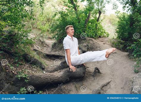 A Young Man Practices Yoga and Performs a Corner Stand on the Roots of an Old Tree. Stock Image ...