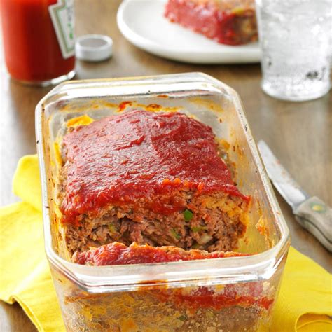 a glass container filled with meatloaf on top of a yellow napkin next to a fork