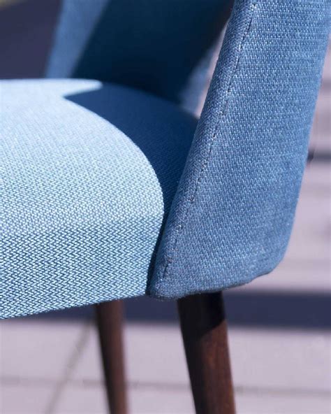 Detail of chair called shell. Warm, brown wood in contrast to the blue upholstery. Detal krzesła ...