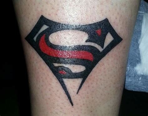 a superman tattoo on the leg of a person with a red and black symbol in the center