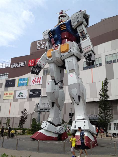 a giant robot statue in front of a building with people standing around ...