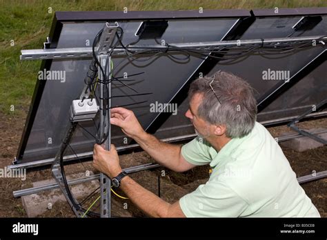 Electrician installing wiring on array of 12 solar hybrid PV panels on ...