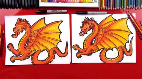 two drawings of yellow and orange dragon sitting on top of a red table next to colored pencils