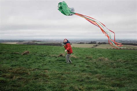 Boy flying kite in a green field on a windy day stock photo