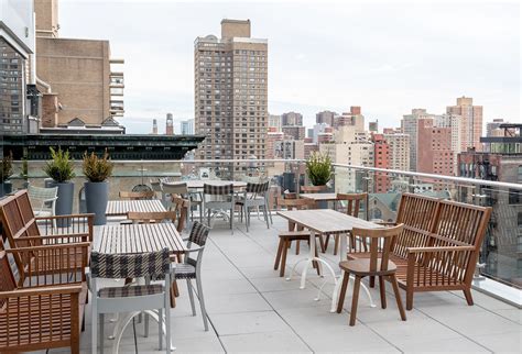 tables and chairs on the roof of a building with city skyline in the back ground