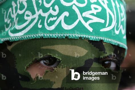 Image of A masked Hamas young girl wearing a headband emblazoned with