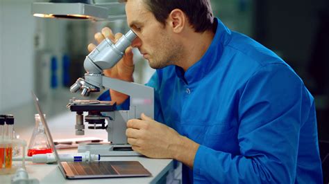 Male scientist looking microscope in lab. Lab man using scientist ...