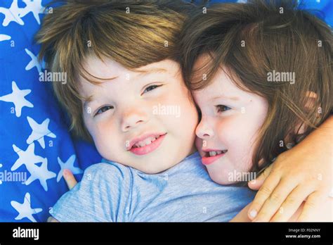 Two children lying on a blanket hugging each other Stock Photo - Alamy