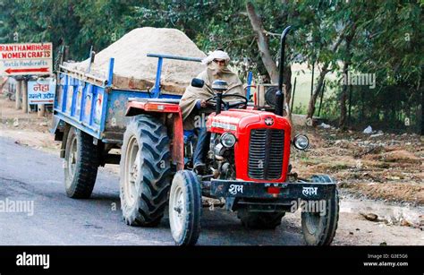 Man driving a red tractor towing trailer India Stock Photo - Alamy