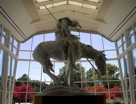 a statue of a man riding on the back of a white horse in front of large ...