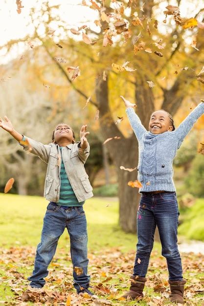 Premium Photo | Portrait of young children throwing leaves around