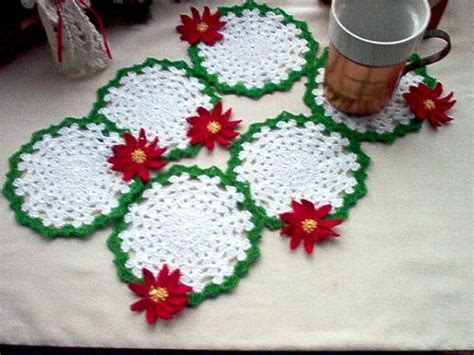 four crocheted coasters with poinsettis on them sitting on a table