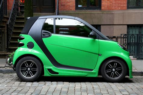 a green smart car parked on the street