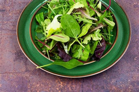 Premium Photo | A bowl of green salad with a green leafy salad on a table.