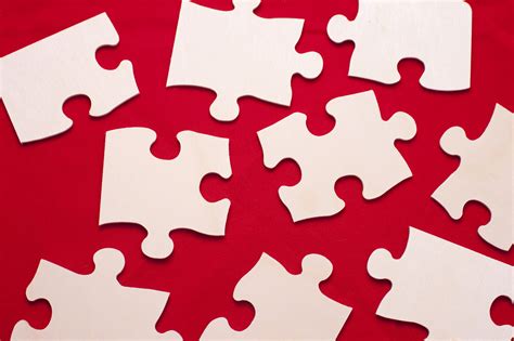 Free Image of Scattered white puzzle pieces on a red background | Freebie.Photography