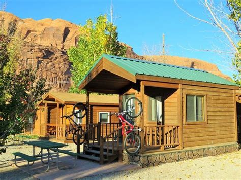 a small wooden cabin with a bicycle on the porch and picnic table in front of it