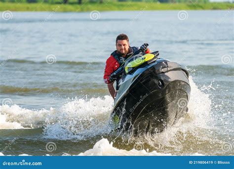 BRP Sea-Doo Jet Ski Watercraft Driver Drives Water Bike Splashing at Sunset by River Bank at ...