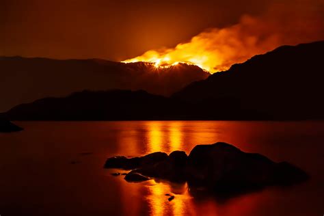 Forest fire at night reflecting in nearby lake. - Drax