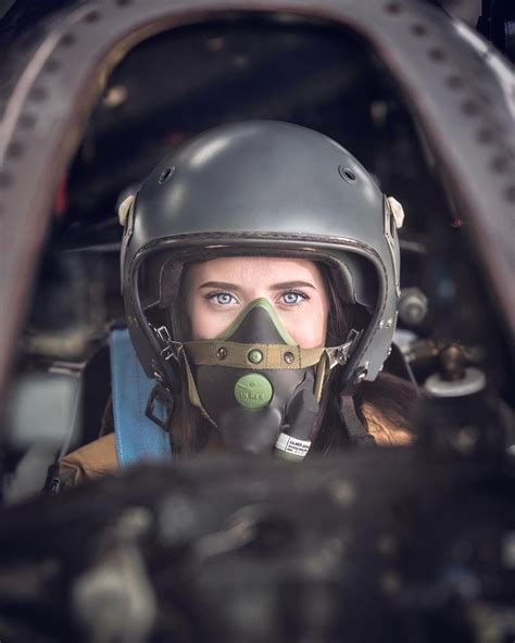 a woman wearing a gas mask sitting in the cockpit of a plane with her face painted green
