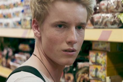 a young man with blonde hair is looking at the camera in a grocery store aisle