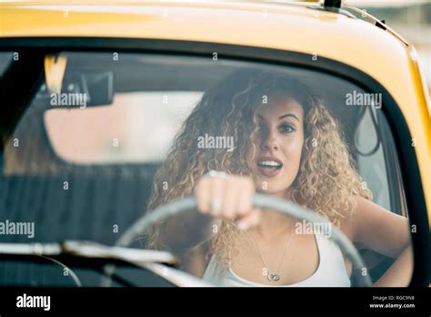 Portrait of surprised blond woman driving classic car Stock Photo - Alamy