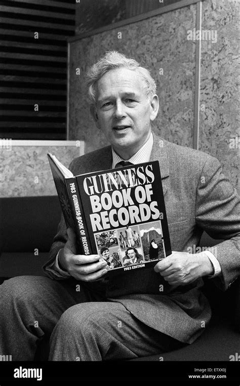 Norris McWhirter holding a copy of the Guinness Book of records, which ...