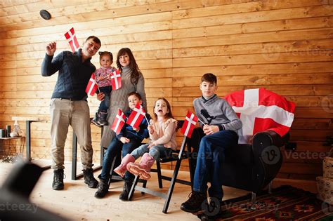 Family with Denmark flags inside wooden house. Travel to Scandinavian countries. Happiest danish ...