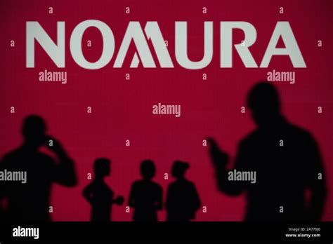 The Nomura logo is seen on an LED screen in the background while a ...