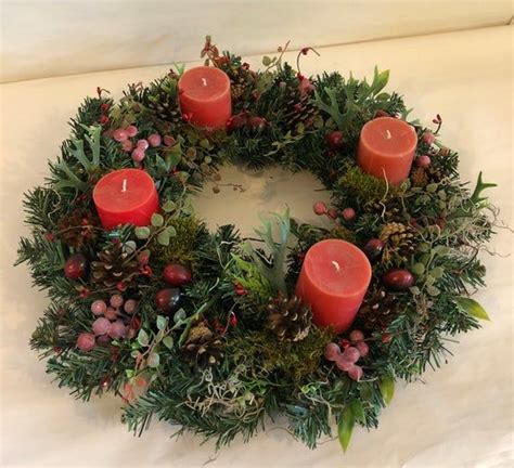 a wreath with candles and greenery on it