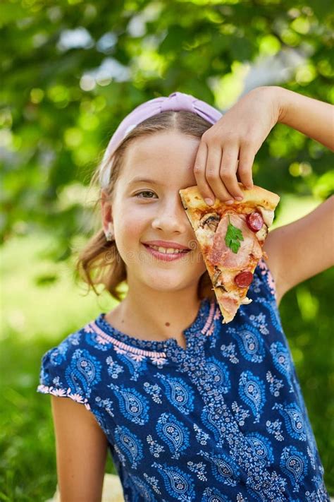 Cheerful Young Girl Enjoying a Slice of Pepperoni Pizza Outdoors on a ...