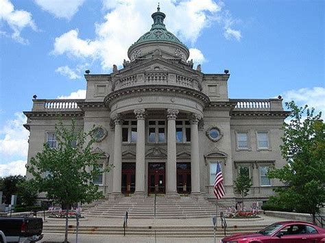 a large building with columns and pillars on the front, surrounded by cars parked in front