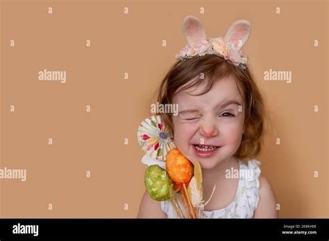 Emotional, positive portrait of little girl with bunny ears on head holding an Easter bouquet of ...