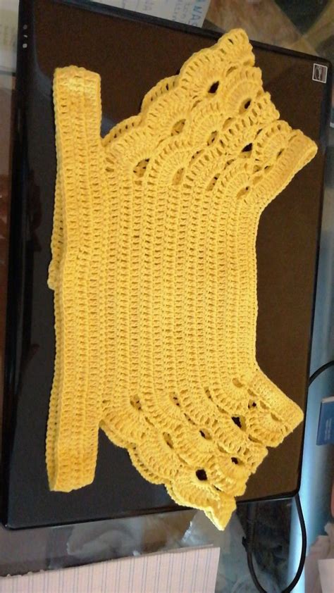 a yellow crocheted piece of cloth sitting on top of a computer monitor screen