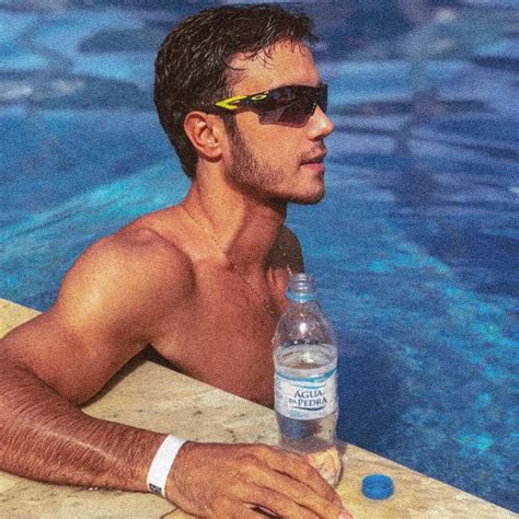 a man sitting next to a swimming pool with a bottle of water in his hand