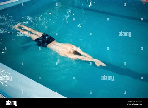 Male swimmer swimming underwater in pool, top view. The man holds his breath in the water ...