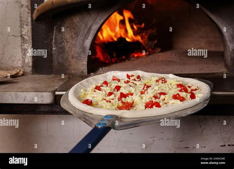 Putting tasty pizza into oven in restaurant kitchen Stock Photo - Alamy