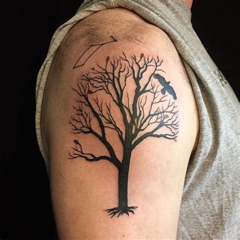 Dark black ink tree with several leaves and roots shoulder tattoo with black crow - Tattooimages.biz