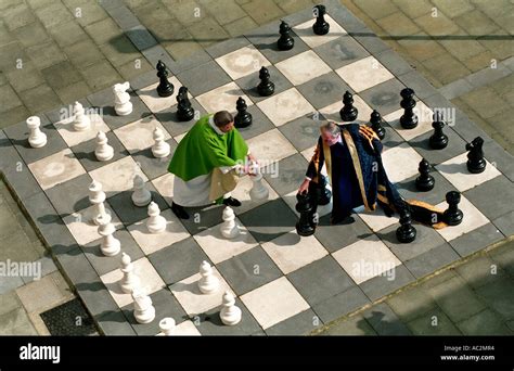 Human scale chess board with a Duke and a Dean in robes playing with giant pieces Stock Photo ...